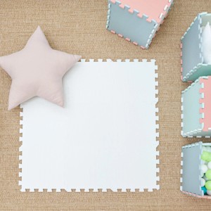 Weiße LittleTom Spielmatte (9 Teile, 30x30 cm) mit Sternkissen und Spielzeugkisten auf Teppich.