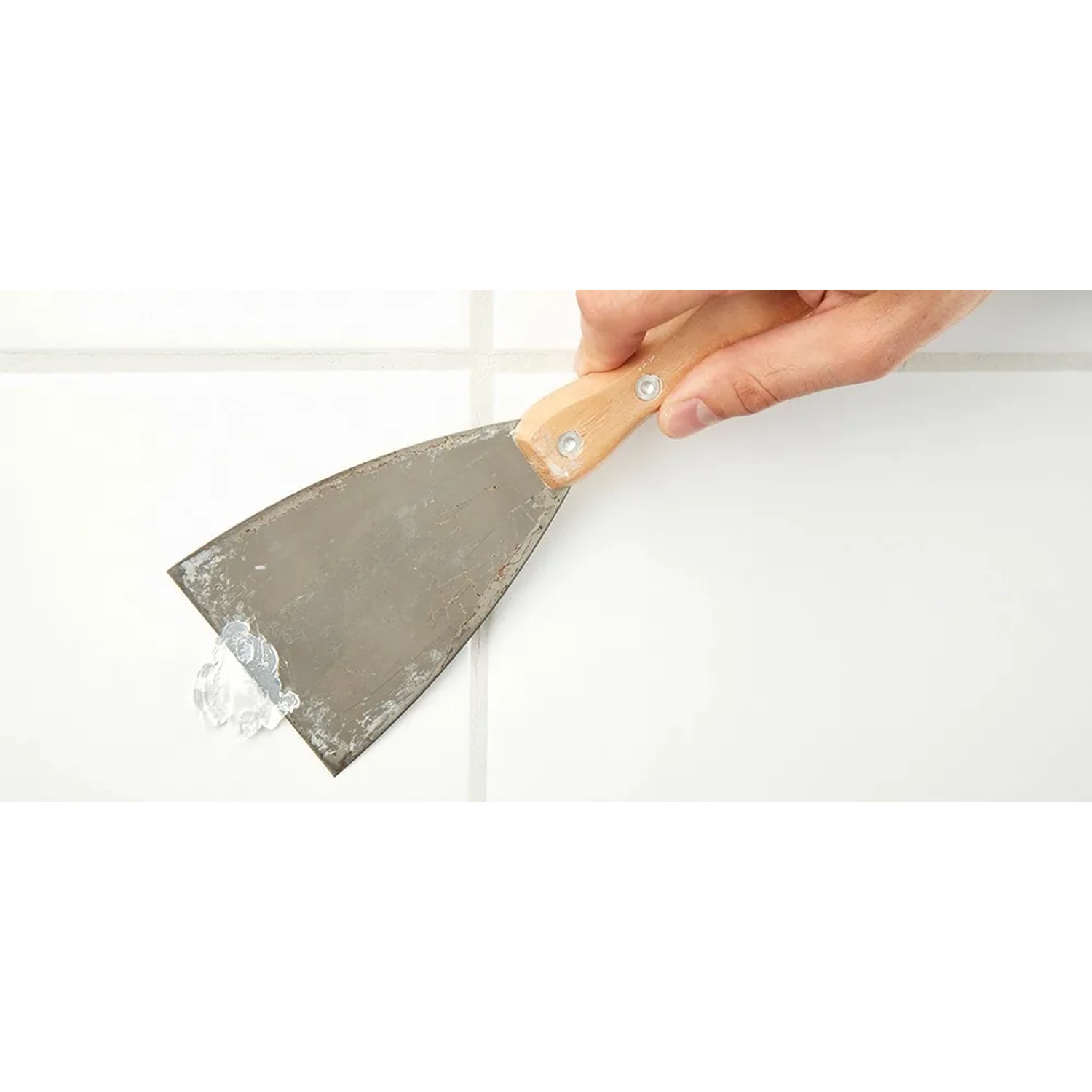 Auftragen von Fischer Bad Kleber auf Fliese mit Spachtel. Kleber für Bad-Accessoires.