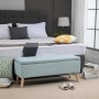 Hellblaue HOMCOM Sitzbank mit Stauraum in Leinenoptik und Holzfüßen vor einem Bett.