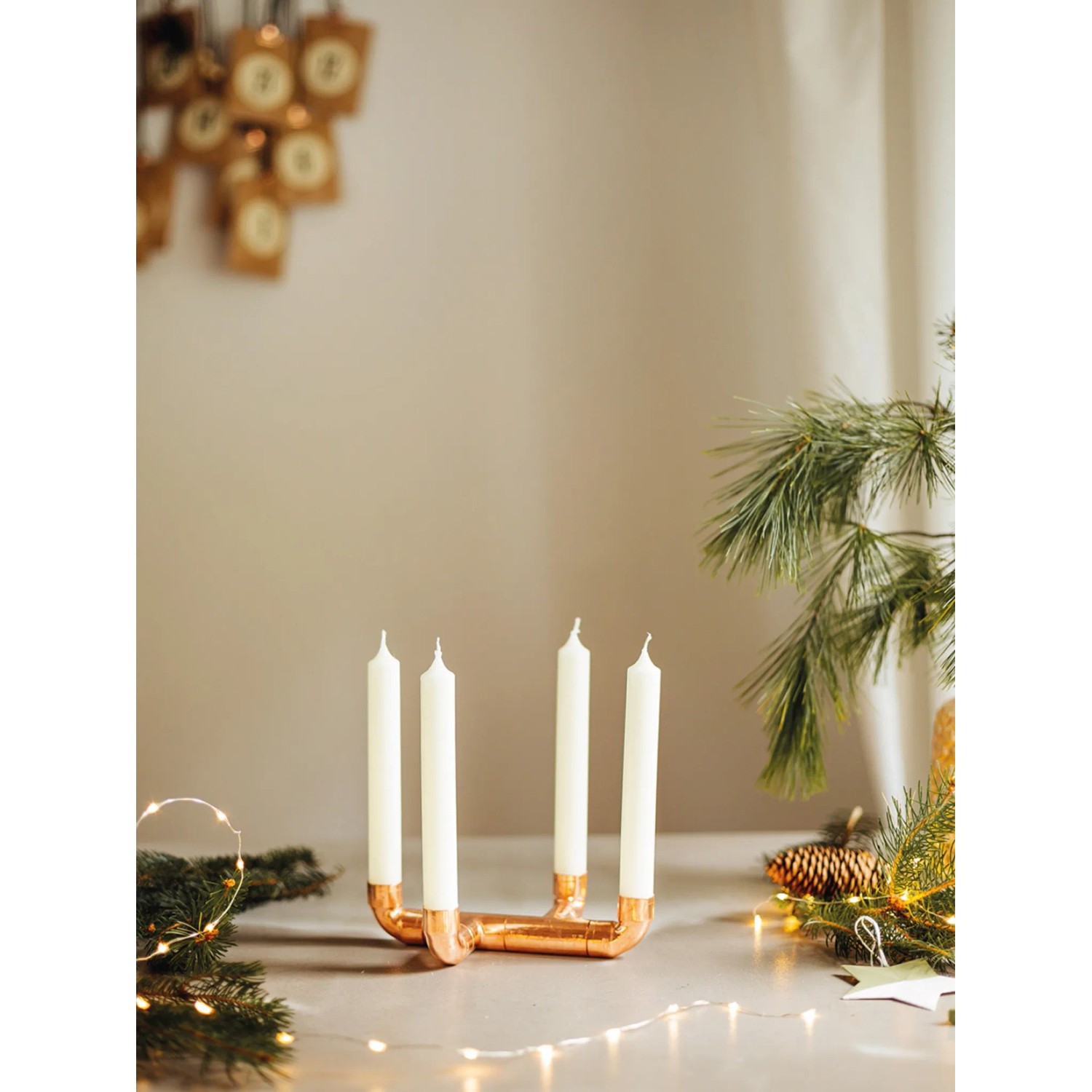 DIY Kerzenständer aus Kupfer mit vier weißen Kerzen, Teil einer weihnachtlichen Dekoration.