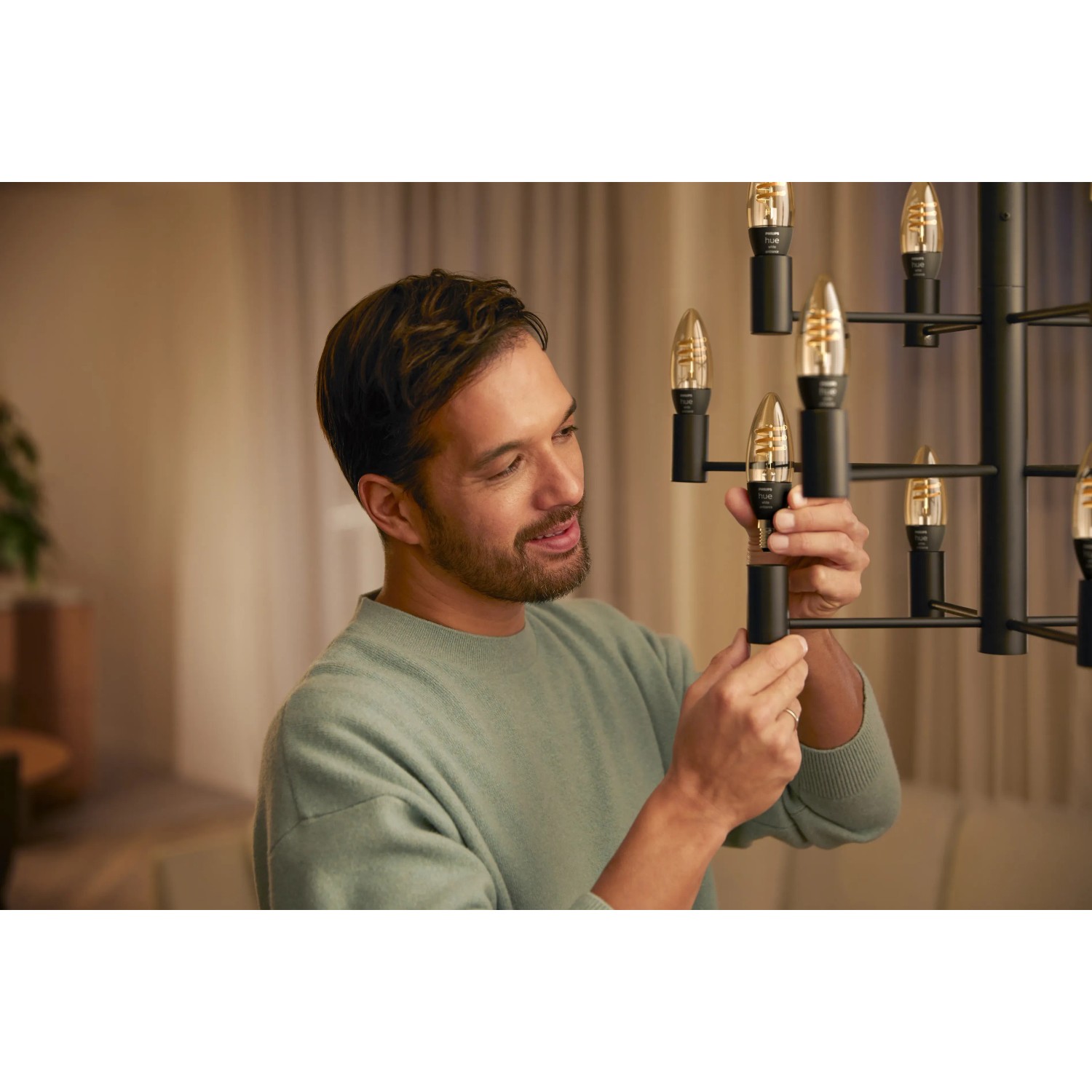 Mann schraubt Philips Hue Filament LED-Kerze E14 in eine Lampe.