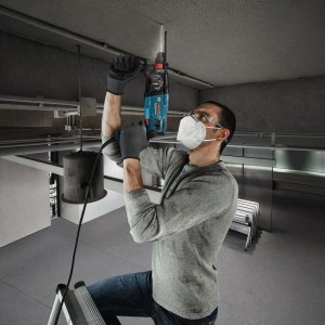 Mann bohrt mit blauem Bosch Professional Bohrhammer GBH 2-21 in Betondecke. Ideal für Bohren, Hammerbohren, Meißeln.