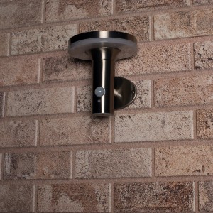 Rostfreie Solar-Wandleuchte Sevilla mit Sensor an einer Backsteinwand.