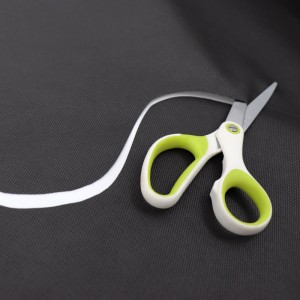 Aquagart Unkrautvlies wird mit einer Schere zugeschnitten.