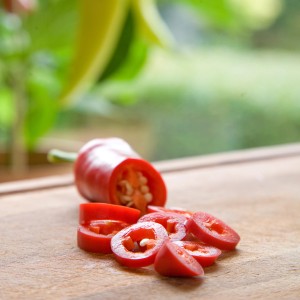 Geschnittener, roter Mini-Chili auf Holzbrett. Fruchtgemüse zum Würzen und Schärfen.