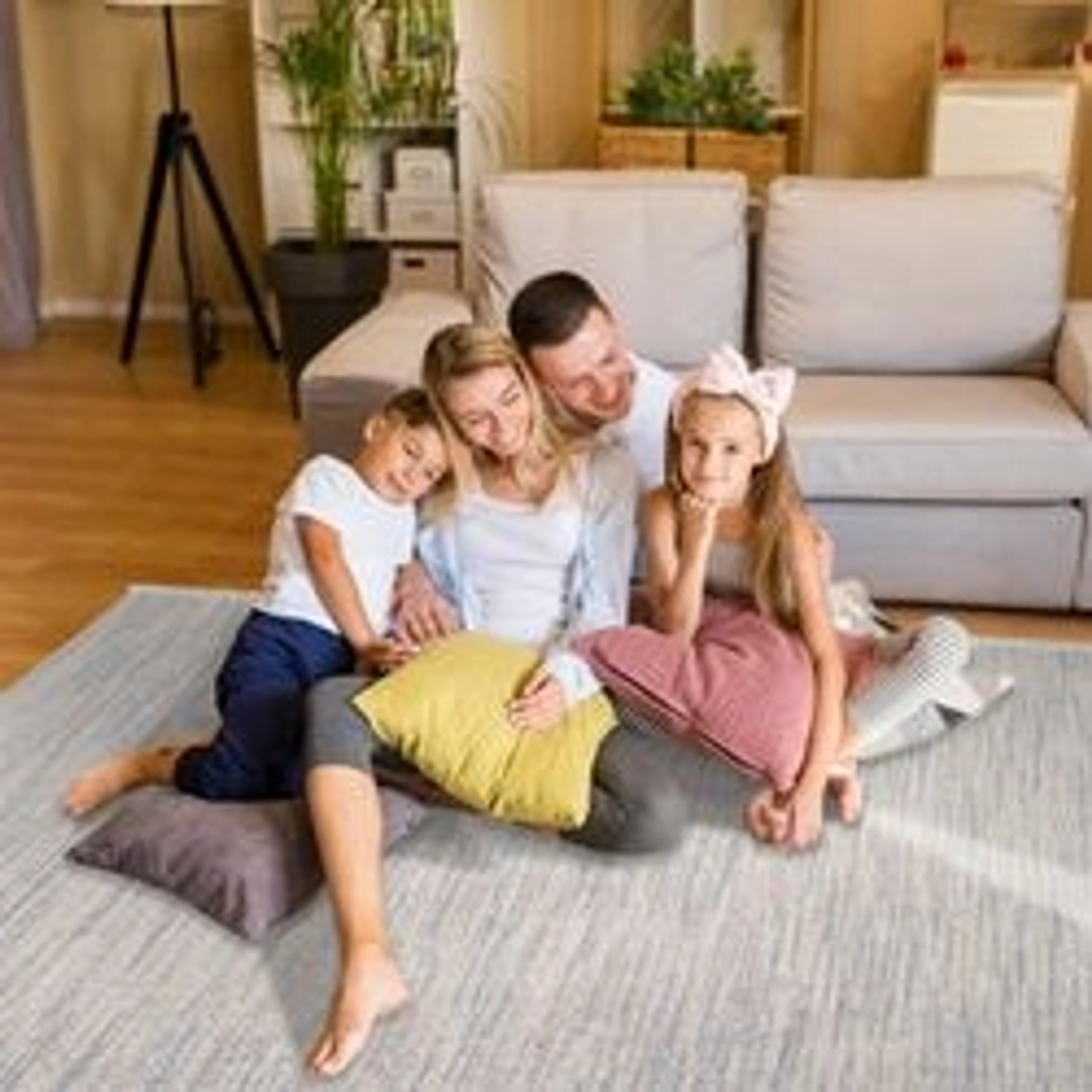 Familie sitzt auf grauem payé Teppich Klassiko 200x290 cm mit Fransen im Wohnzimmer.