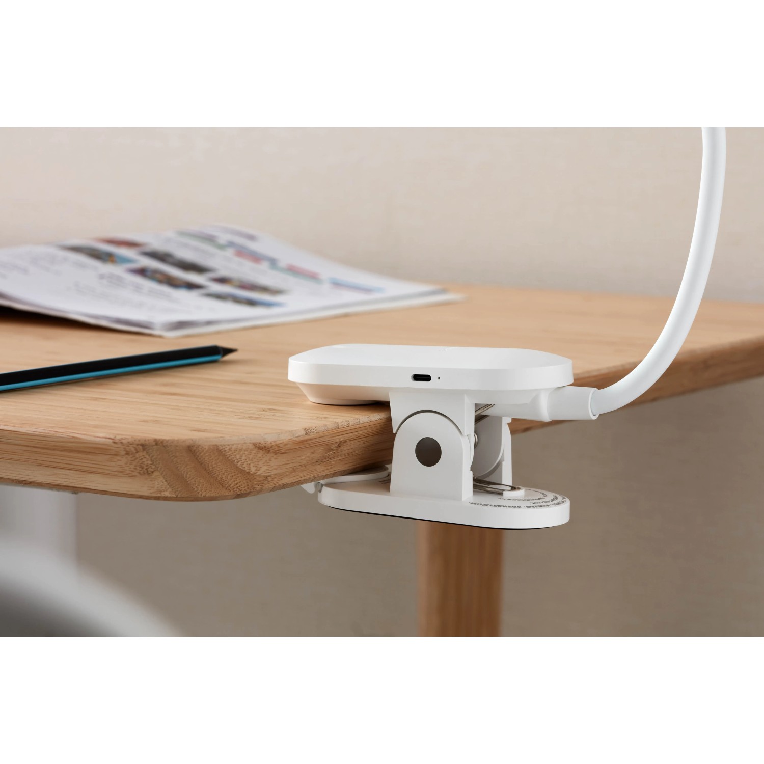 Weiße Philips LED-Tischleuchte Forys mit Clip am Tisch befestigt. Akkubetriebene Schreibtischleuchte.