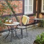 Runder, grauer Siena Garden Gartentisch Stella (Ø 70 cm) mit Stuhl auf einer Terrasse.