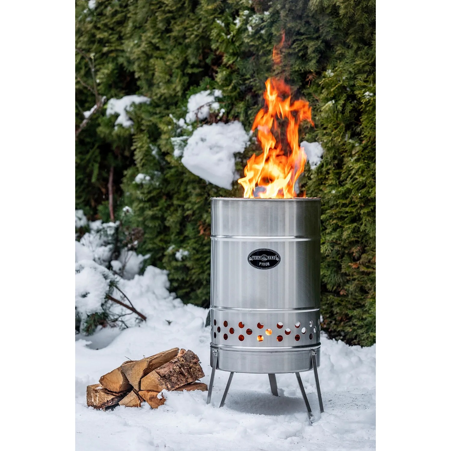 Feuerhand Pyron Feuertonne aus Edelstahl, 25 l, mit brennendem Feuer im Schnee.