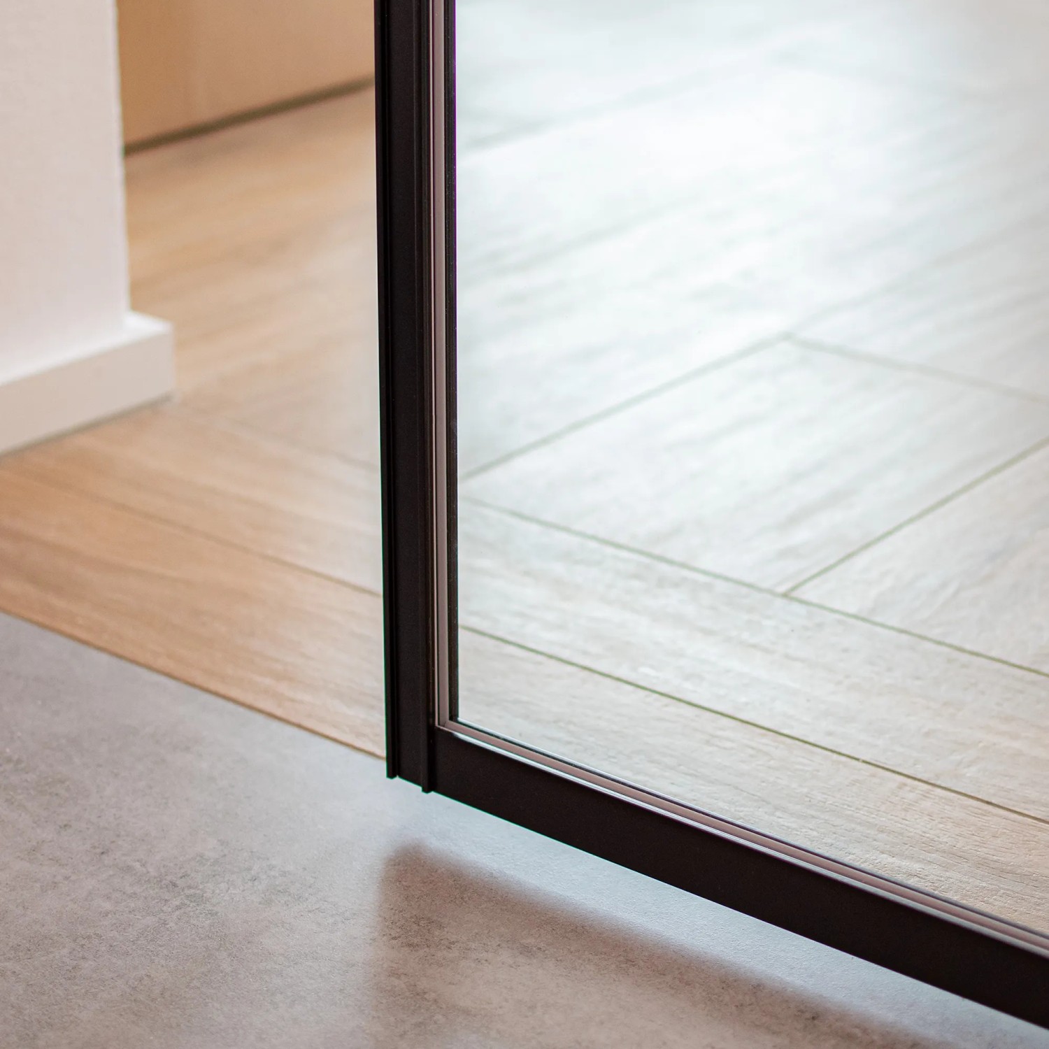 Detailaufnahme: Schwarze inova Loft Glasschiebetür mit Alu-Profil im Raum.