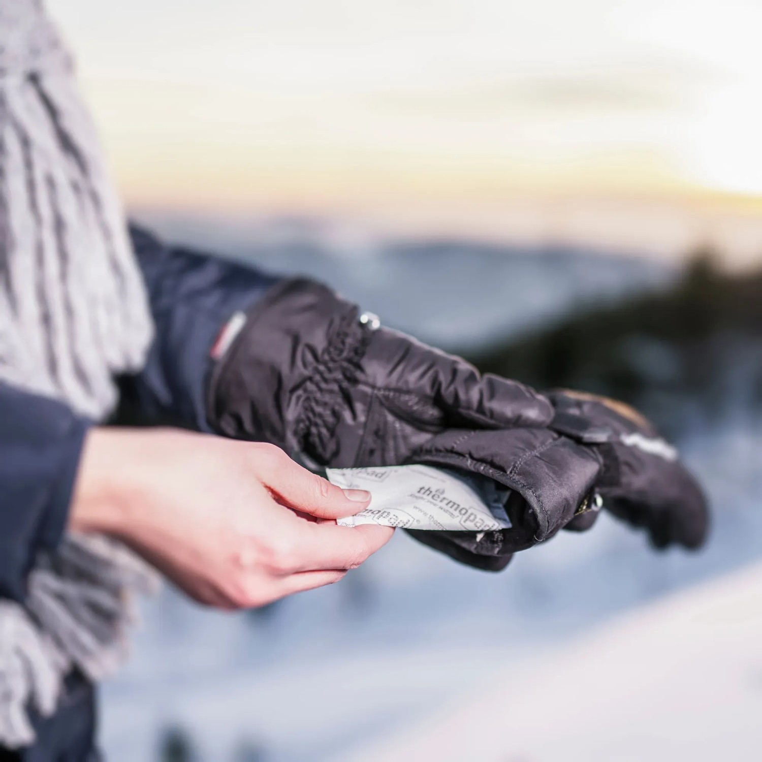 Frau hält Thermopad Handwärmer (5 Paar) in Handschuh. Wärmedauer 12h. Ideal für Arbeitskleidung.
