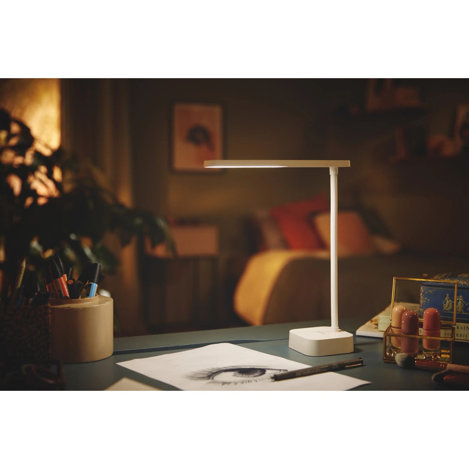 Weiße Philips LED Schreibtischleuchte Tilpa mit Akku auf einem Schreibtisch.