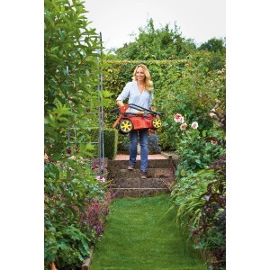 Frau trägt roten Wolf-Garten Elektro-Rasenmäher A 340 durch Garten.