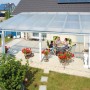 Transparente Acryl Stegdoppelplatte als Terrassenüberdachung mit Familie im Garten.