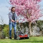 Einhell Akku-Spindelmäher GE-HM 18/38 Li-Solo im Einsatz im Garten unter blühendem Baum.