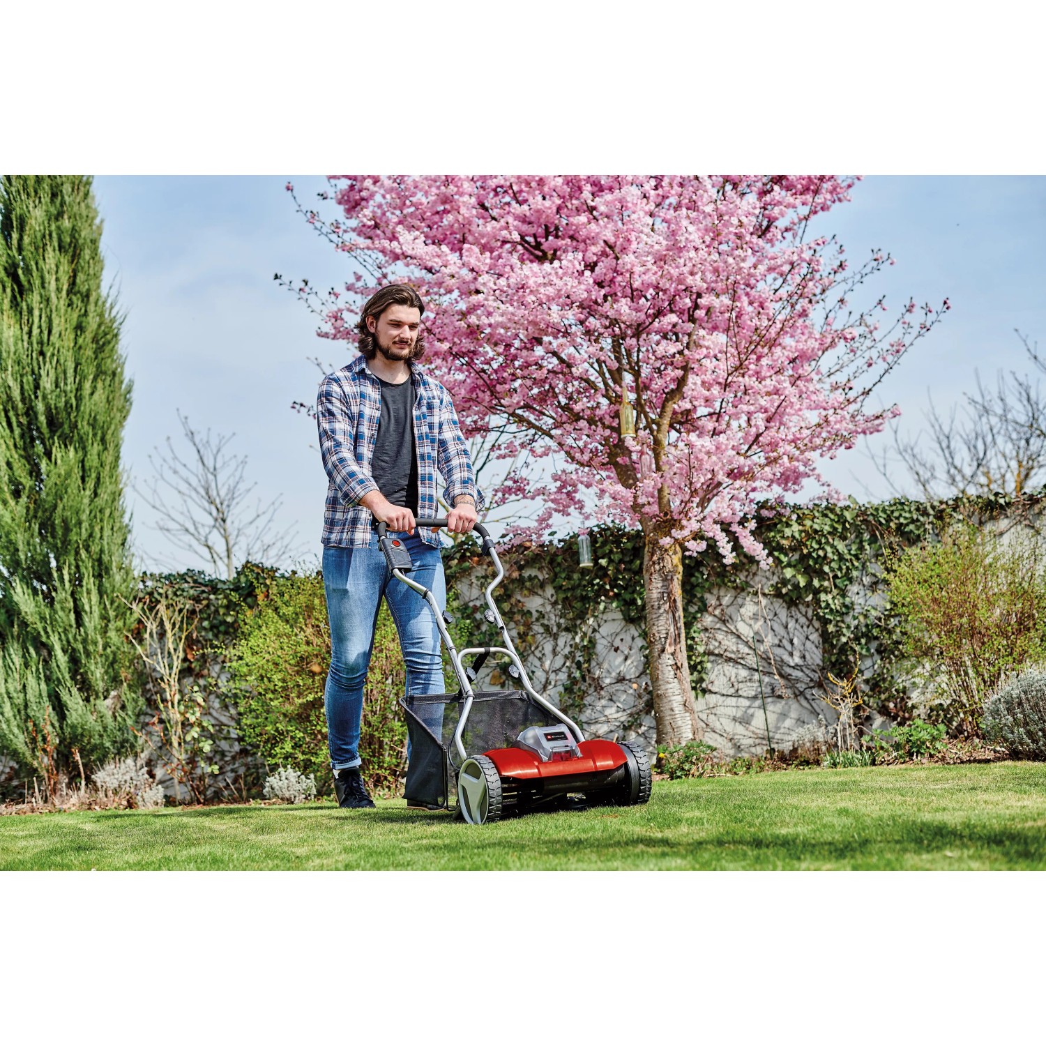 Einhell Akku-Spindelmäher GE-HM 18/38 Li-Solo im Einsatz im Garten unter blühendem Baum.