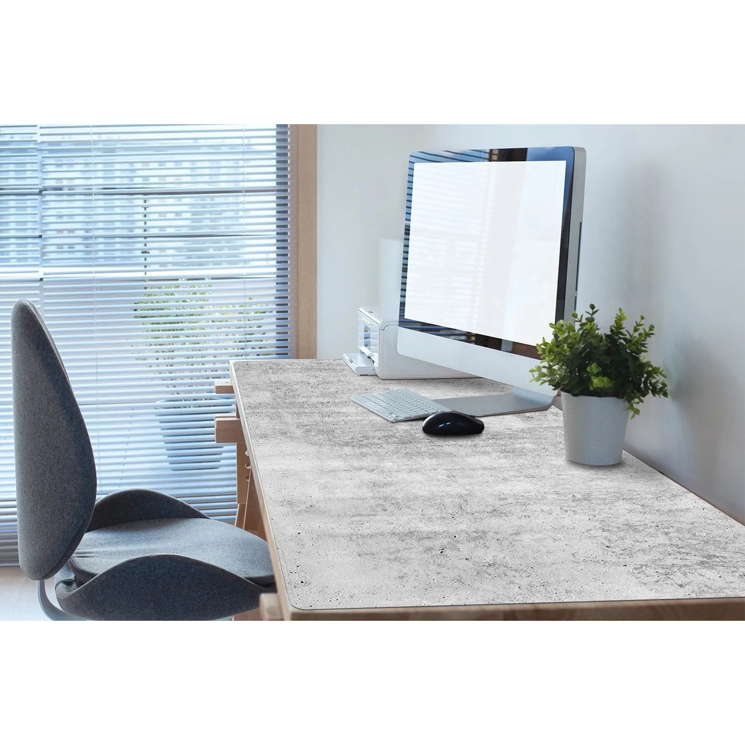Graue Beton Schreibtischunterlage auf einem Holzschreibtisch mit Monitor und Maus. Schützt die Arbeitsfläche im Büro.