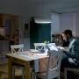 Philips LED-Lampe E27, 6,5W, neutralweiß im Einsatz über Esstisch mit Person am Laptop.