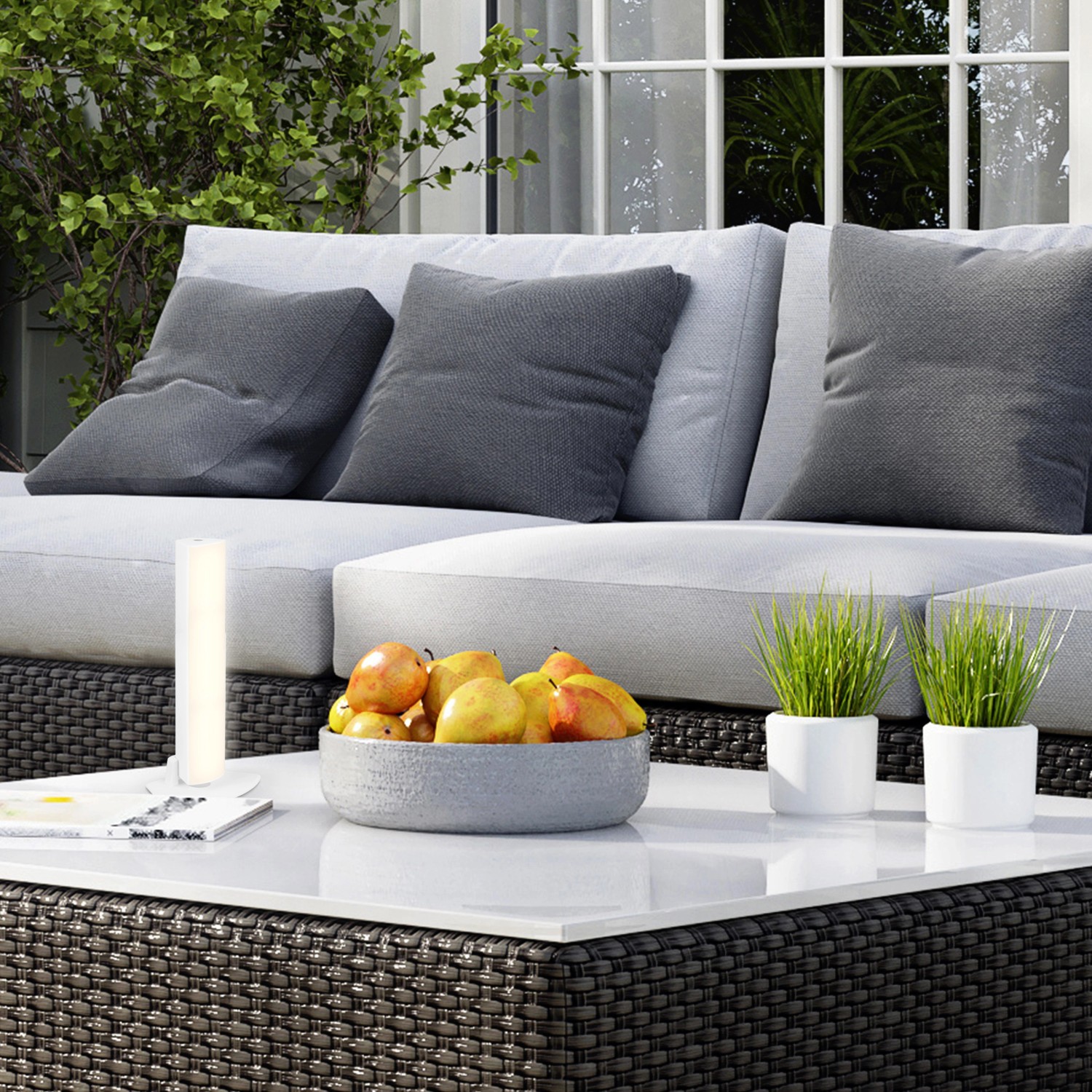 Brilo Akku Tisch- und Wandleuchte Zadar Weiß auf Gartentisch mit Deko.