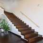Runder Aluminium Handlauf in Buche-Optik mit Wandhalterungen an einer modernen Holztreppe im Treppenhaus.