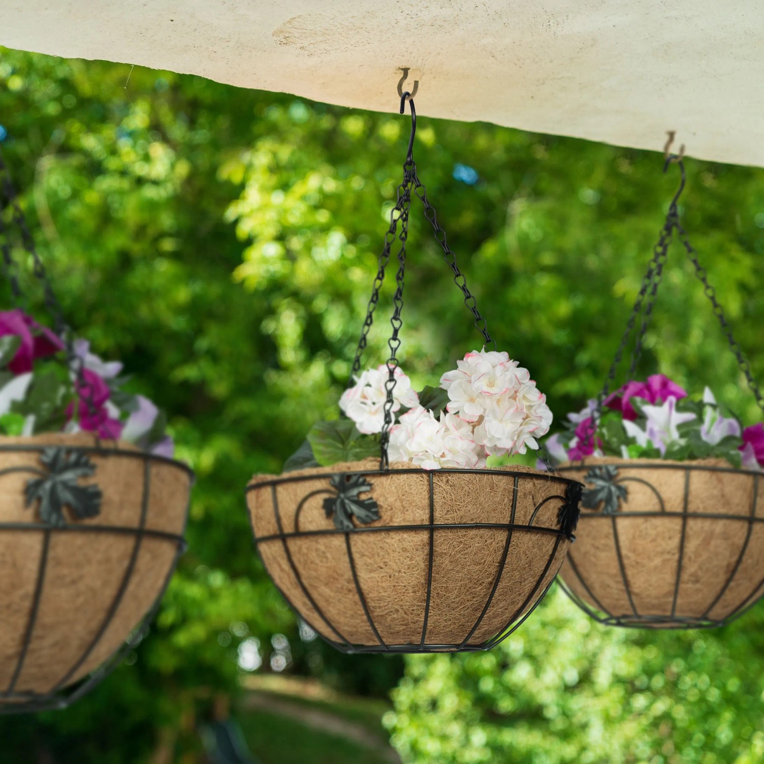3er Set Relaxdays Blumenampeln aus Eisen und Kokosfaser, schwarz und natur, mit bunten Blumen bepflanzt.