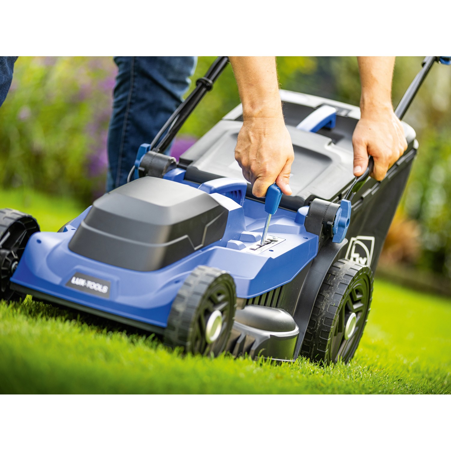 LUX-TOOLS Elektro-Rasenmäher E-RM-1800/43 in Aktion: Schnitthöhenverstellung auf Rasenfläche.