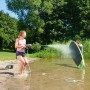 Frau reinigt Surfbrett mit Worx Hydroshot Akku-Mitteldruckreiniger am See.
