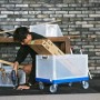 Blauer Eurobox-System Rollwagen 60x40 cm mit transparenter Box und Person bei Montagearbeiten.