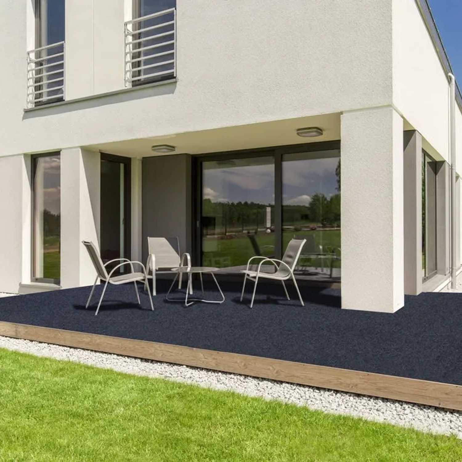 Schwarzer Karat Rasenteppich Farbwunder PRO auf Terrasse mit Gartenmöbeln.