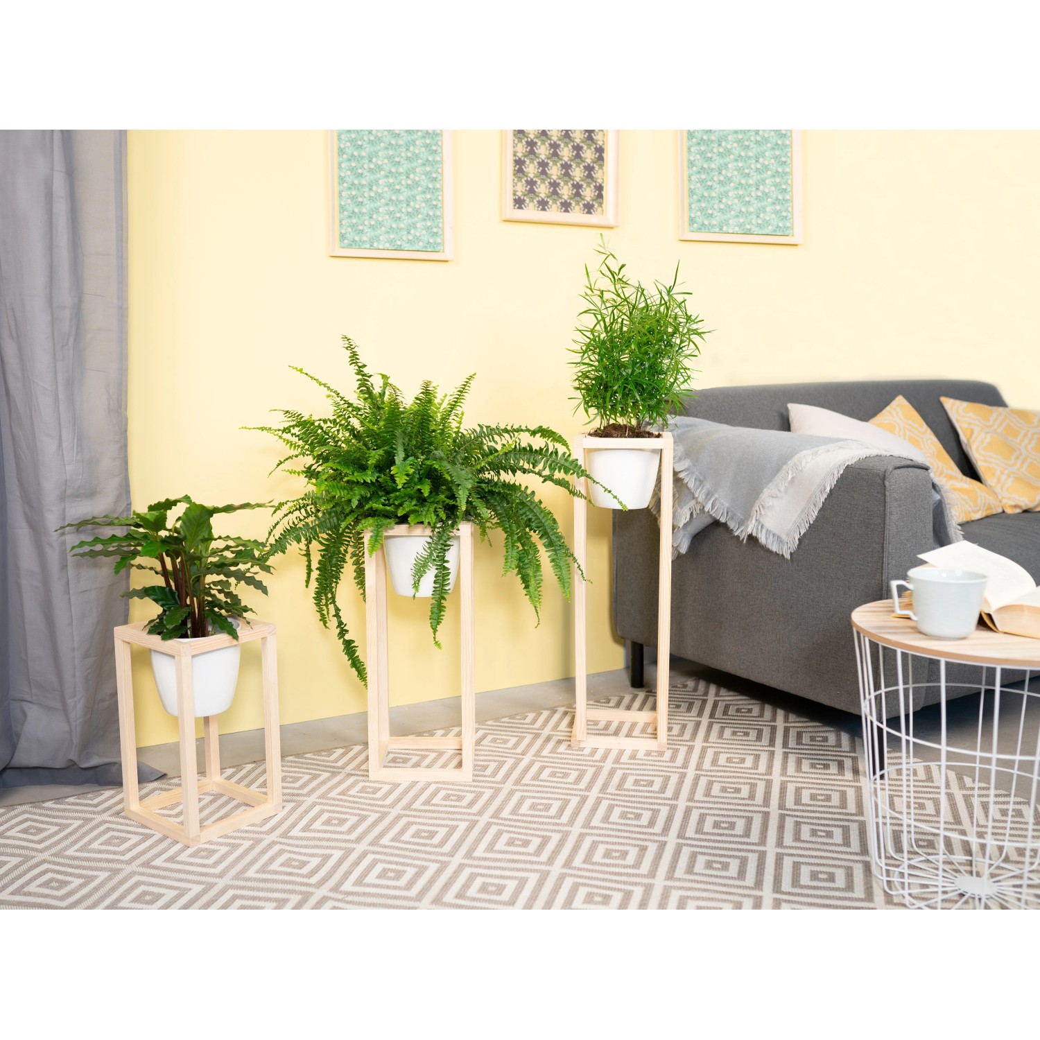 DIY Pflanzständer Set von CREATE! by OBI mit drei Pflanzen in weißen Übertöpfen auf Holzgestellen.