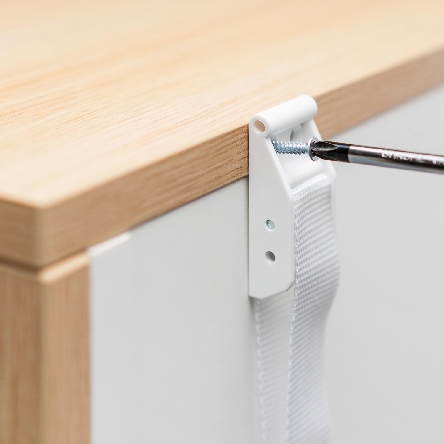 Montage der Reer Möbel-Kipp-Sicherung mit Schraube an einem Möbelstück.