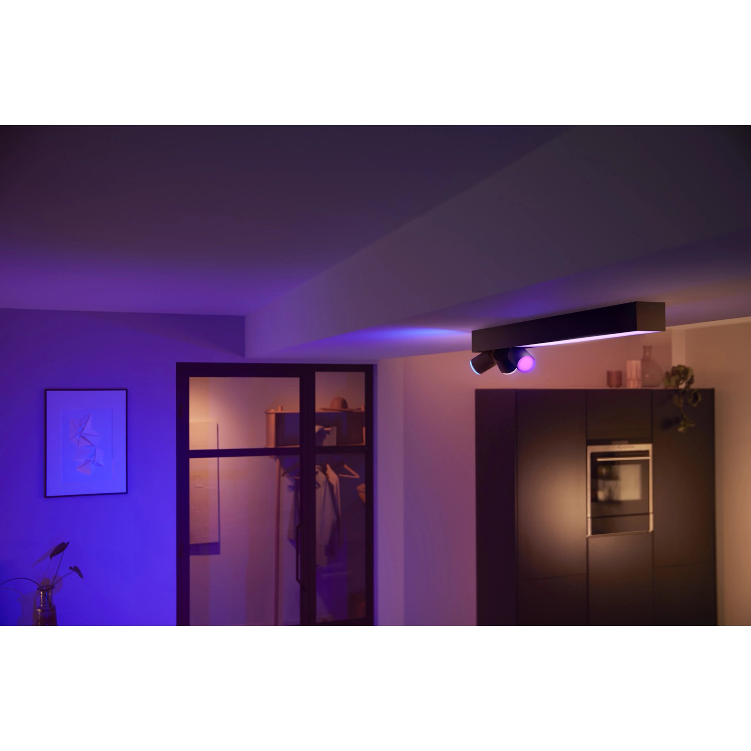 Schwarze Philips Hue Centris LED-Deckenleuchte mit 3 Spots in farbig beleuchtetem Raum.