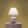 Gelbe Tadessi Uni Vliestapete als Wandhintergrund, beleuchtet von einer Lampe auf einem Nachttisch. Dekorative Tapete.