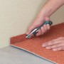 Wolfcraft Profi-Messer schneidet Teppichboden. Sicherheitsmesser mit Trapezklinge im Einsatz.