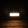 Schwarze LED Solar-Außenleuchte mit Sensor, 10W, 1080lm, 3000K an einer Backsteinwand.