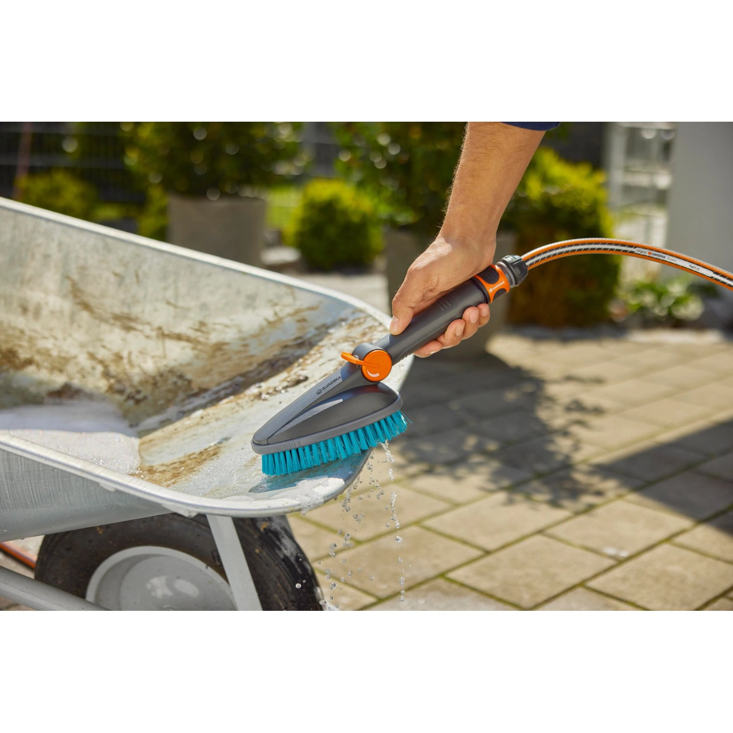 Gardena Cleansystem Handbürste Hard M mit Schlauchanschluss beim Reinigen einer Schubkarre.
