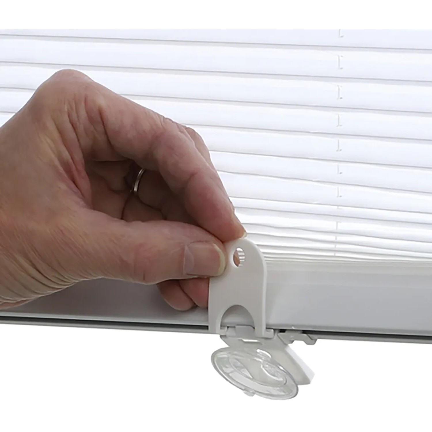 Weißes Gardinia Dachfenster-Plissee mit Saugnäpfen in der Hand, Detailaufnahme.