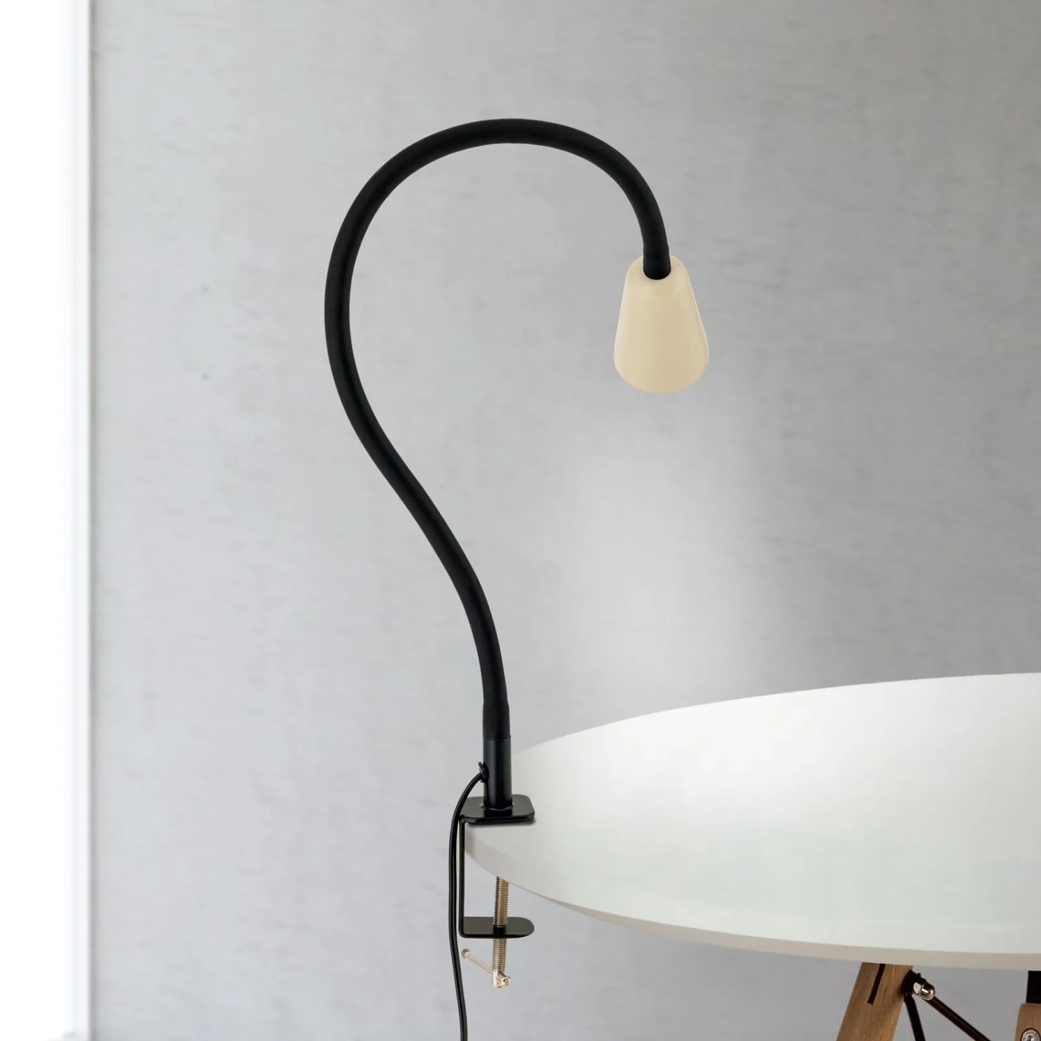 Orion Klemmleuchte Dotty mit schwarzem Schwanenhals und beigem Kopf, an weißem Tisch geklemmt. GU10 Innenleuchte.