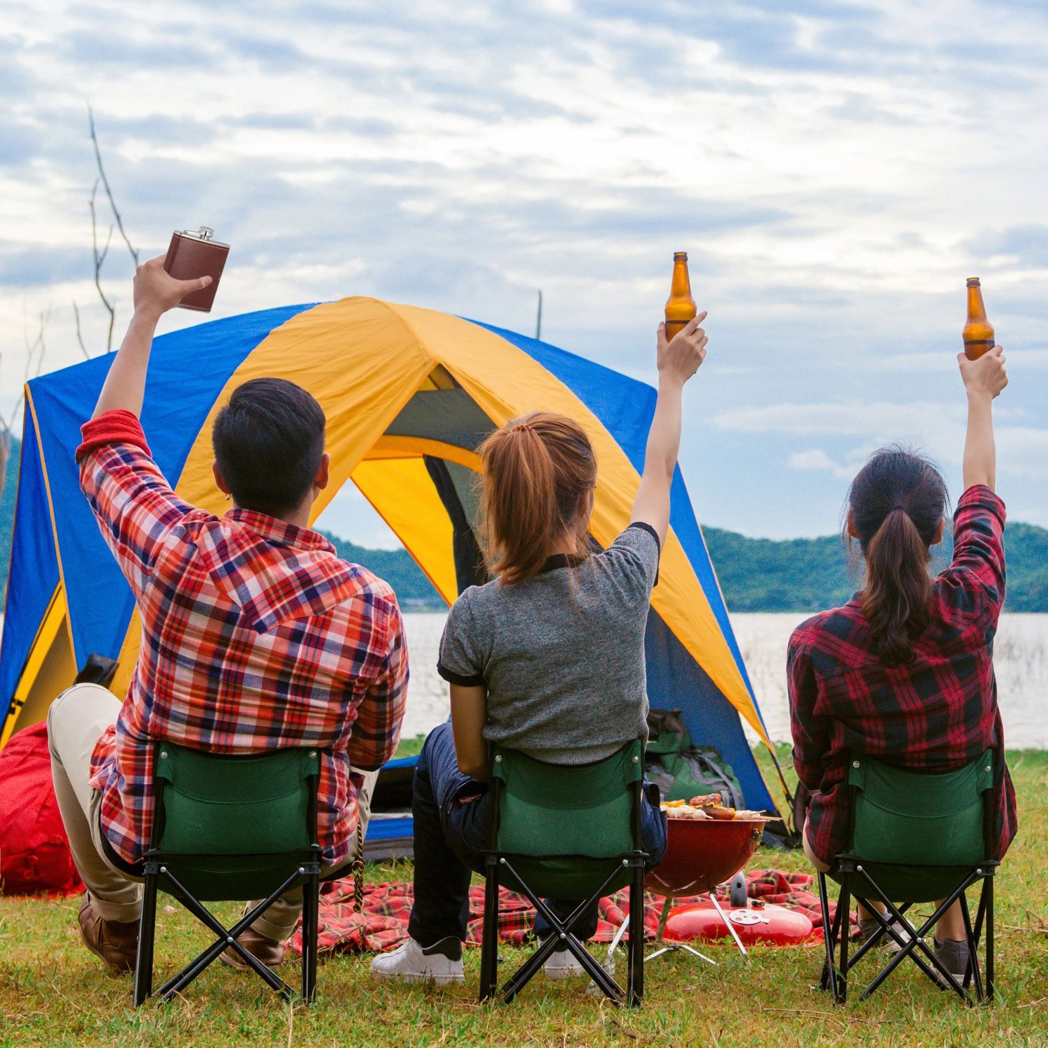 Person hält braunen Relaxdays Flachmann aus Edelstahl mit Kunstlederhülle beim Camping am See.