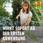 Frau gießt Blumen mit Compo Universal-Blumendünger für üppige Blüten.