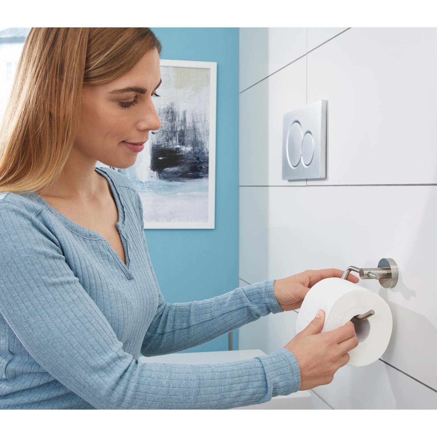 Frau bestückt Tesa Toilettenpapierhalter Moon in Edelstahloptik mit Toilettenpapier.