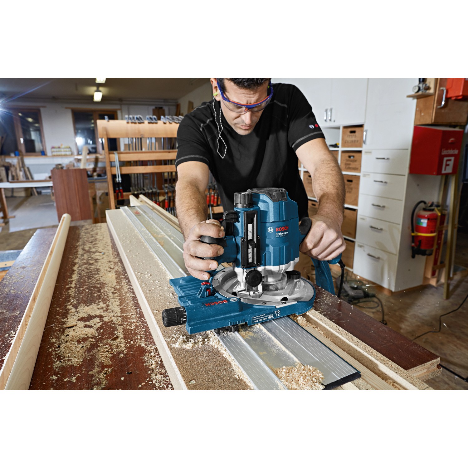 Bosch Professional GOF 1250 CE Oberfräse im Einsatz, mit Spanner und Staubabsaugung.