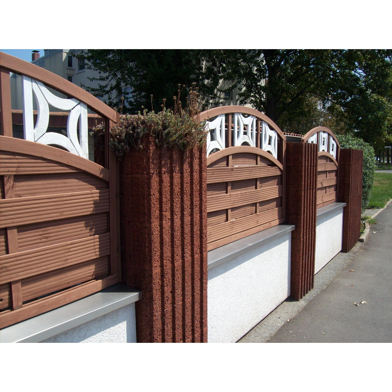 Brauner Pflanzstein 60x40x25 cm als Teil einer Gartenmauer mit Holzzaun.