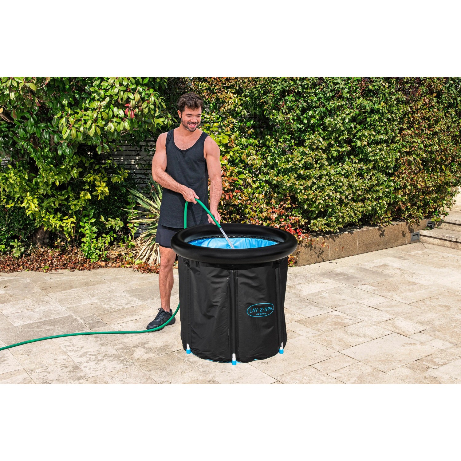 Bestway LAY-Z-SPA Eisbad Glacial Zen, ein Mann befüllt den schwarzen, runden, aufblasbaren Whirlpool mit Wasser.