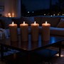 Vier coffeefarbene Relaxdays LED-Echtwachskerzen mit flackernder Flamme auf einem Couchtisch.
