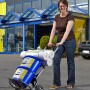 Frau transportiert Farbeimer und Rollen mit der klappbaren wolfcraft Sackkarre TS 850 (100 kg) vor dem OBI Markt.