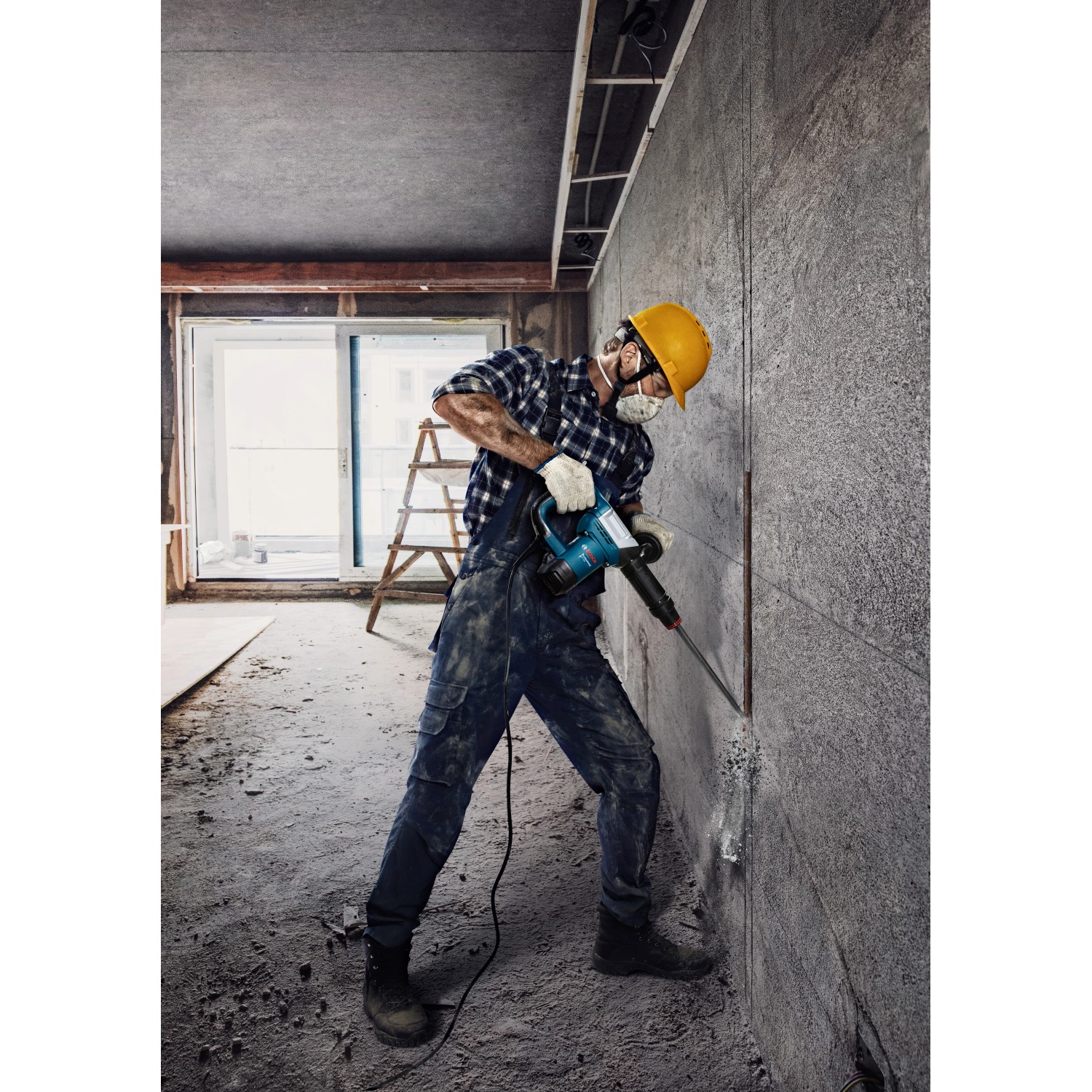 Handwerker mit Bosch Professional Bohrhammer GSH 5 CC beim Stemmen einer Wand.
