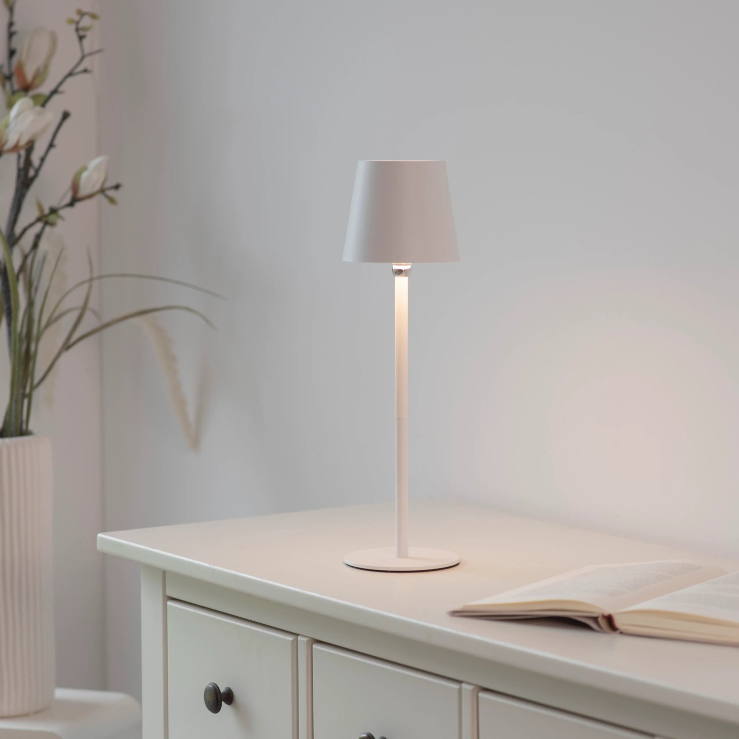 Weiße Just Light Akku-LED-Tischleuchte Boteria auf Kommode. Dekorative Außenleuchte mit Touchdimmer.