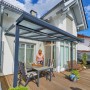 Anthrazit Terrassenüberdachung Bausatz (306x306cm) mit Polycarbonatplatten und montierter Sitzgruppe auf Terrasse.