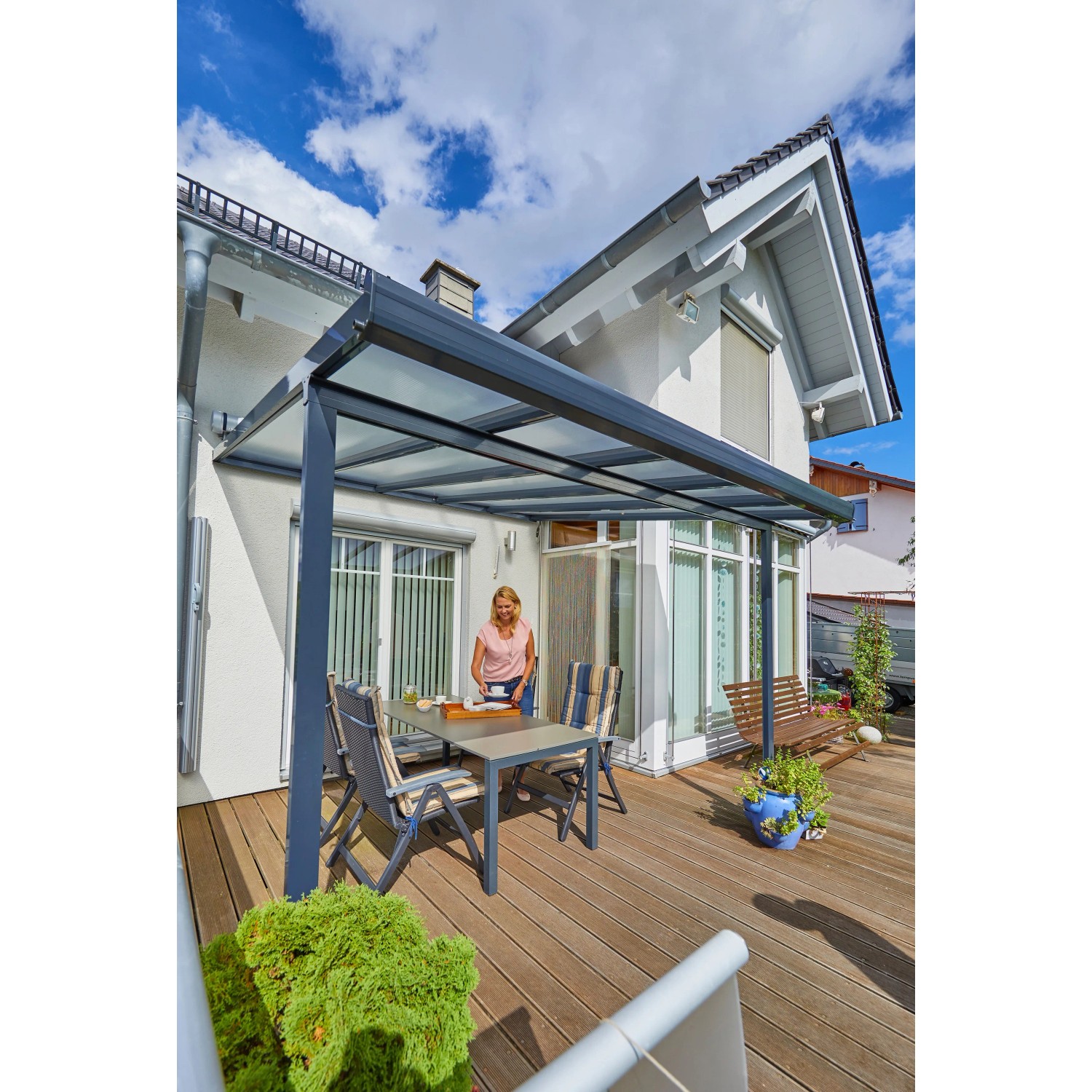 Anthrazit Terrassenüberdachung Bausatz (306x306cm) mit Polycarbonatplatten und montierter Sitzgruppe auf Terrasse.